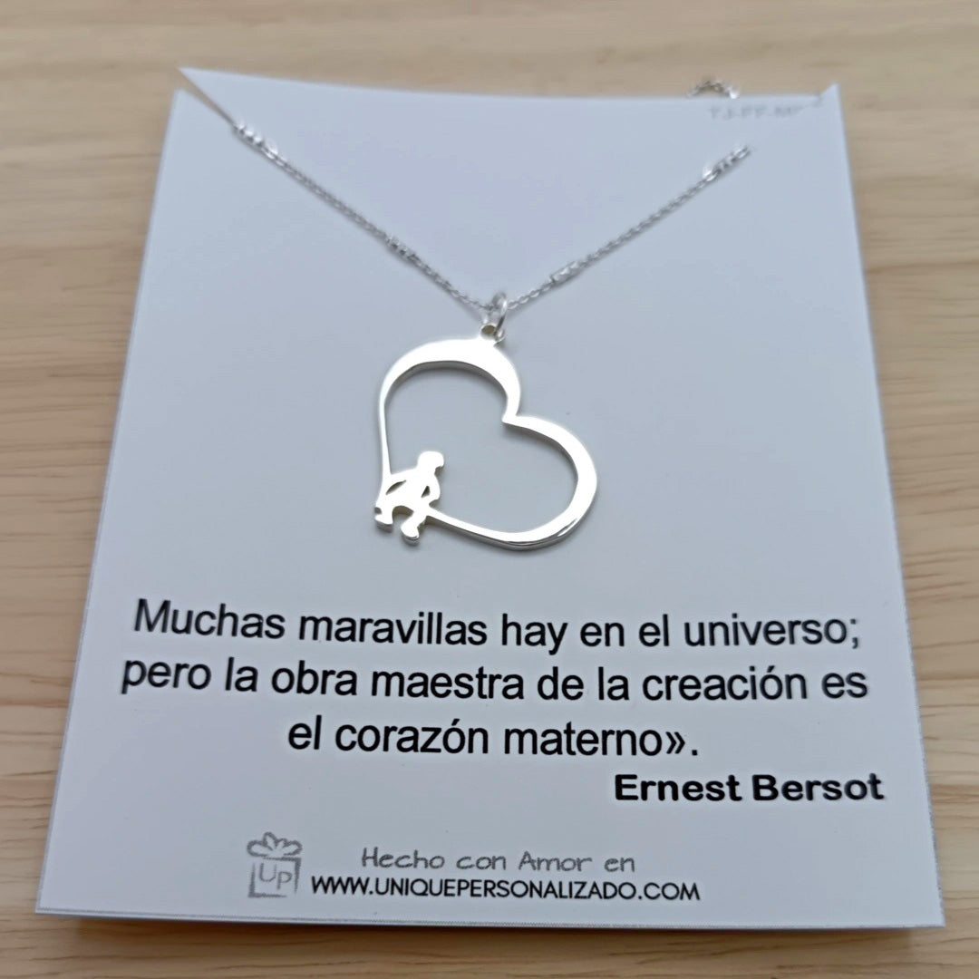 Vista frontal de la cadena con dije de corazón y figuras de niños sentados, en acabado brillante.