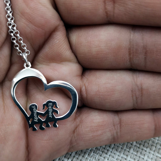 Cadena con colgante de corazón y figuras de niños sentados, símbolo del amor eterno de mamá.