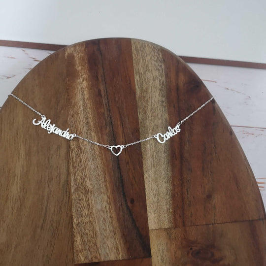 Detalle del colgante con nombres personalizados y corazón central, representando un vínculo único e inquebrantable.